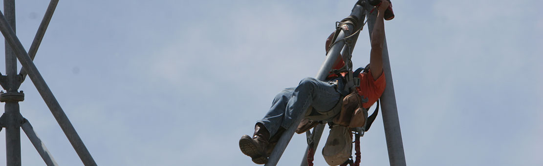 Men connected to safety cables doing some antenna tower checks