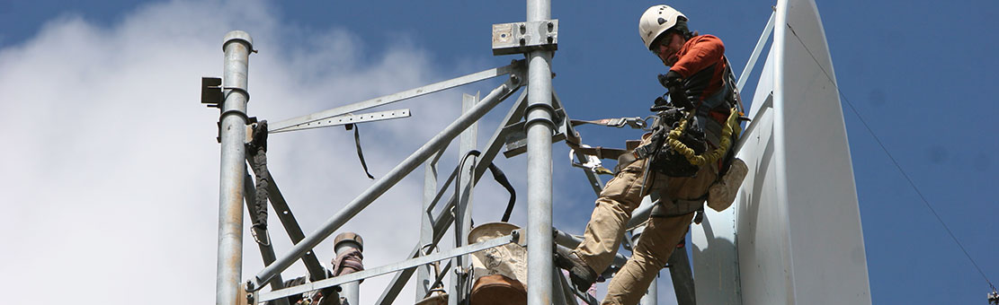 Men connected to safety cables doing some antenna dish checks