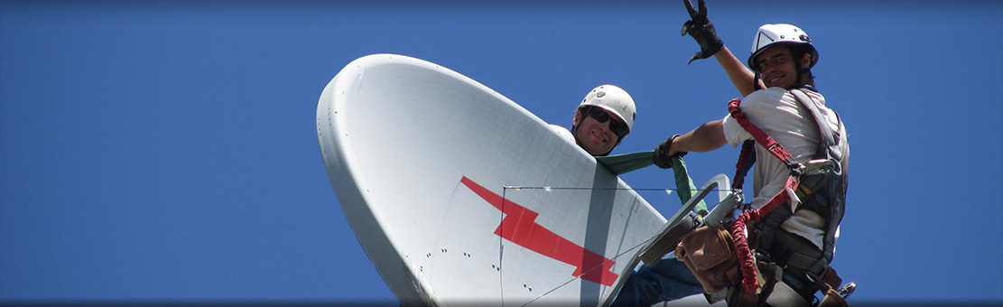 Men connected to safety cables doing some antenna dish checks